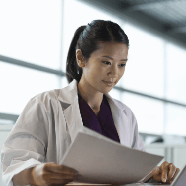 Woman in white lab coat looking at a file